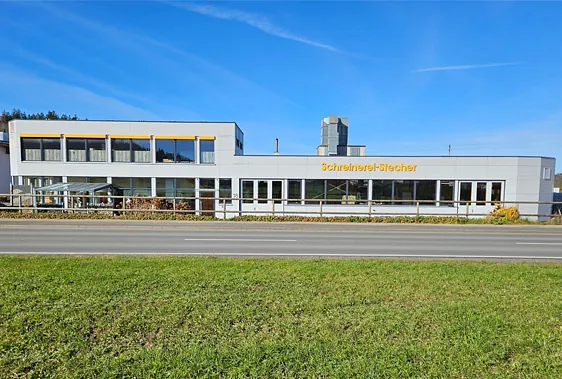 Fassade eines weißen Gebäudes mit den Schriftzügen Schreinerei-Stecher' in Gelb.